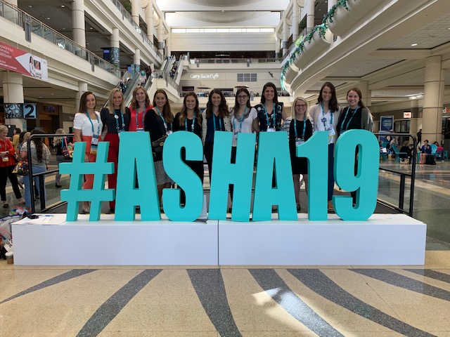 SLHS students behind a large art installation of block letters that spell #ASHA19