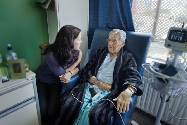social worker visits elderly patient in clinical setting
