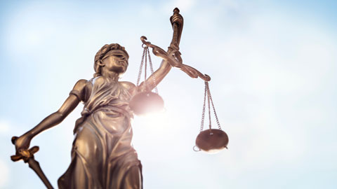 statue of lady justice holding scales against blue sky