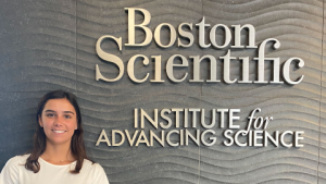 Health Science alumna Elizabeth LaDriere stands in front of the Boston Scientific sign where she interned and now works full time