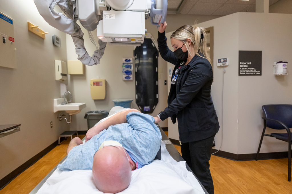 SHP Radiography Program junior Kiley Bailey palpates the side of a patient to make sure the X-ray tube is lined up in the correct anatomy before taking an image of his abdomen.