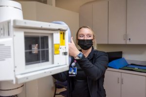 Kiley Bailey holds the handle of the X-ray tube to control the movement of the machine while taking an image of a patient.