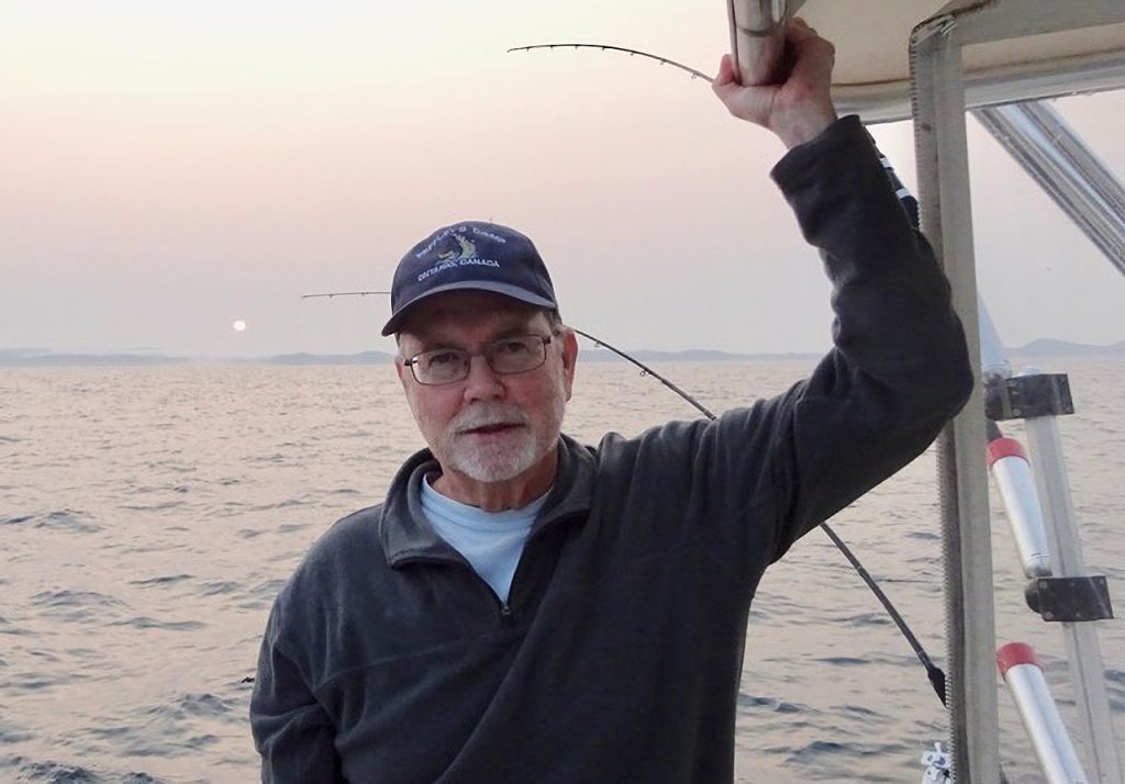 A man poses on a boat while fishing