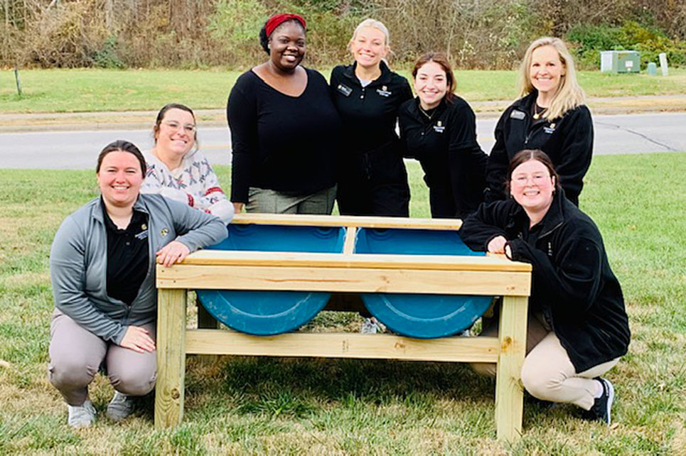 A group of women stand near raised garden beds