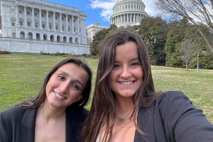 Two young women pose in front of the United States Capitol