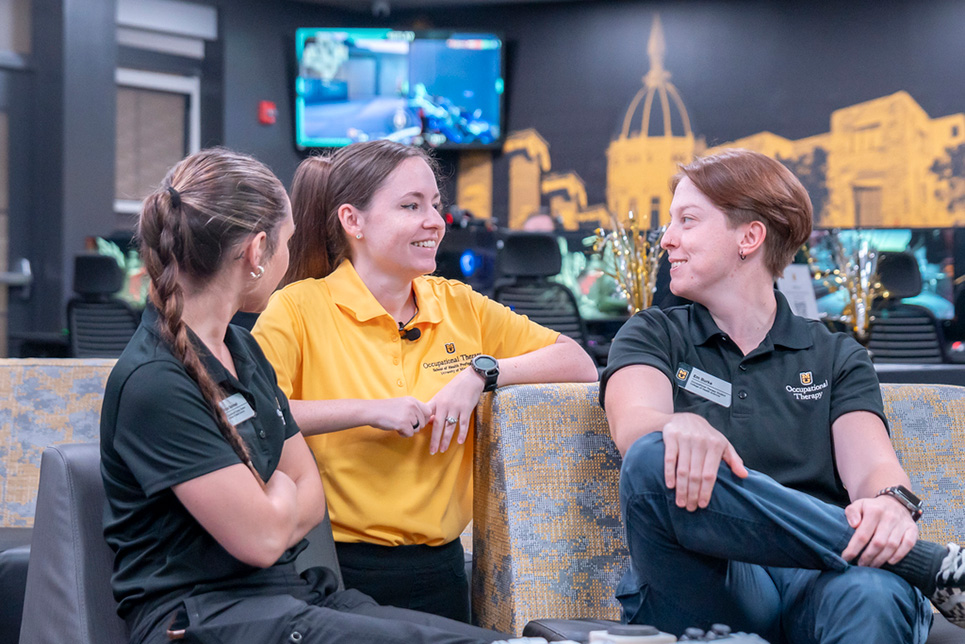 Three young women talk while sitting in a gaming lounge