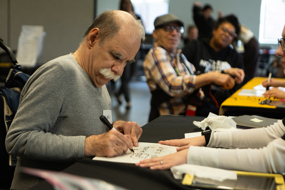 A man writes a message on a whiteboard to communicate with a student clinician