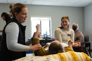 Two young women work with a physical therapy patient reclined on a table