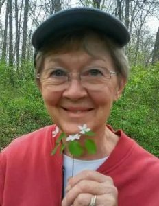 A woman smiles while holding a flower