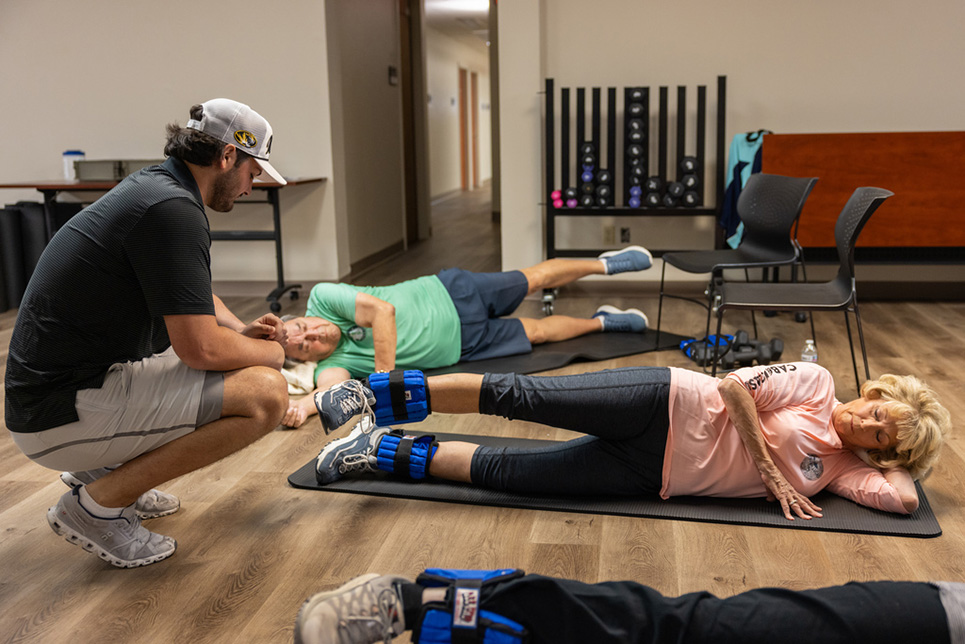 A young man coaches two older participants in a fitness class