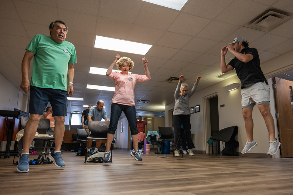 A group of fitness class participants do jump squats