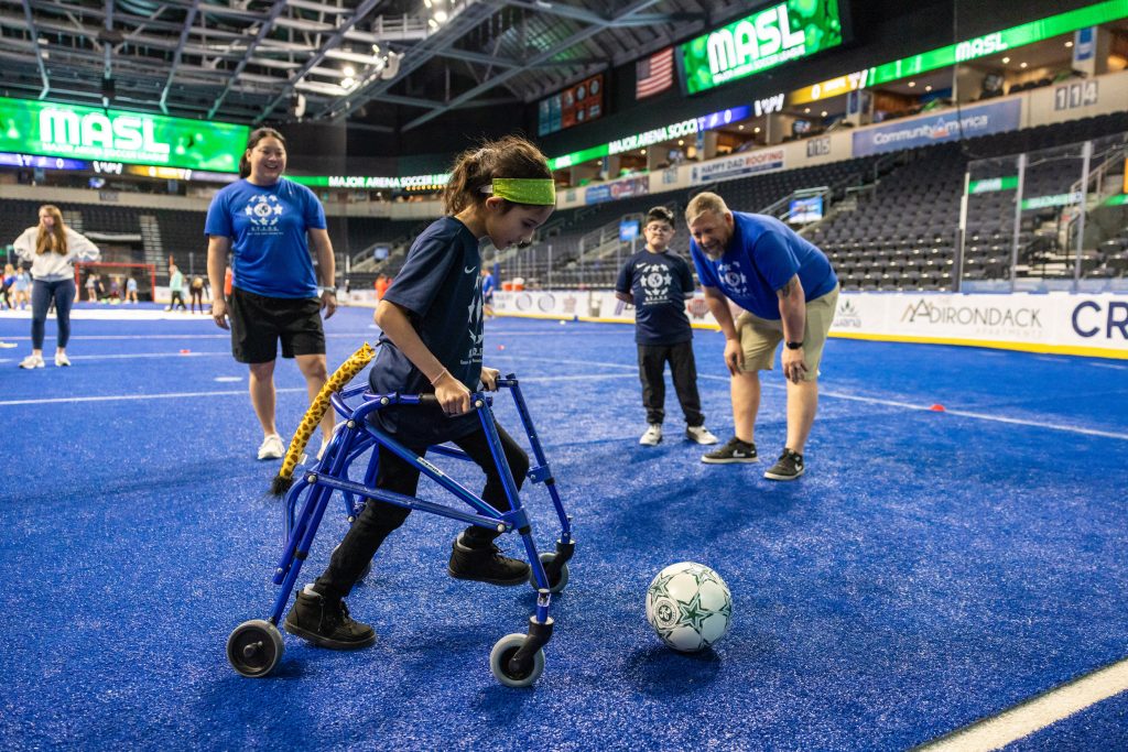 A child using a walker kicks a soccer ball