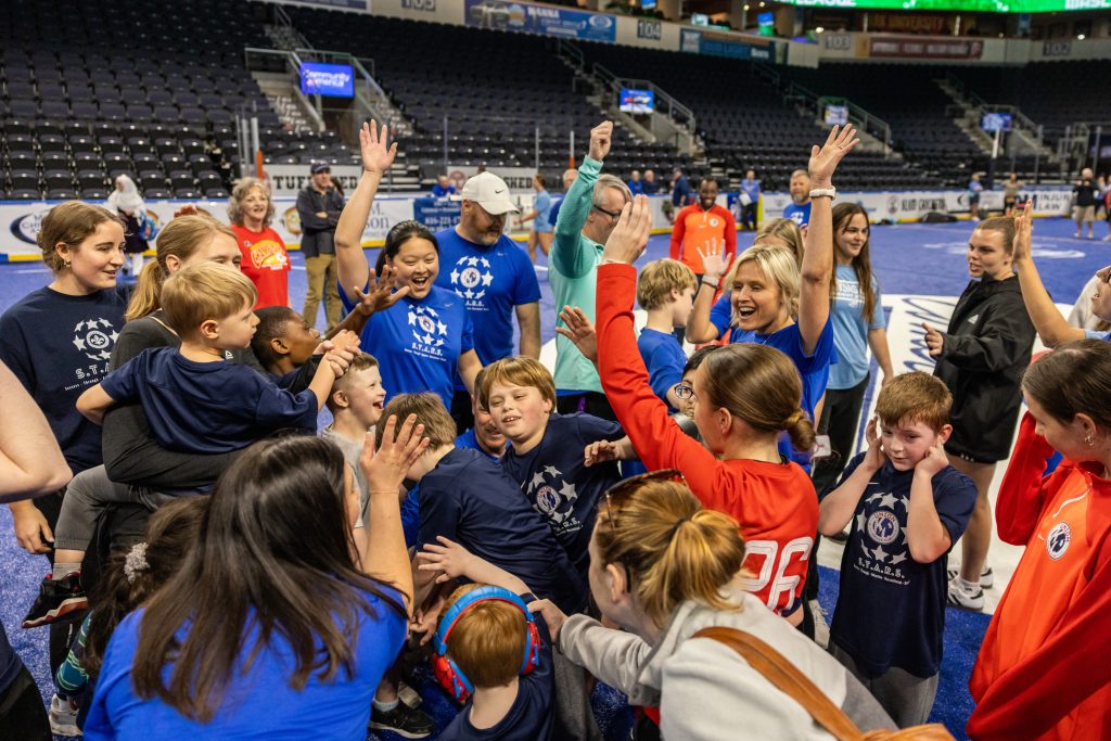 A group of players and coaches join together to cheer after practice