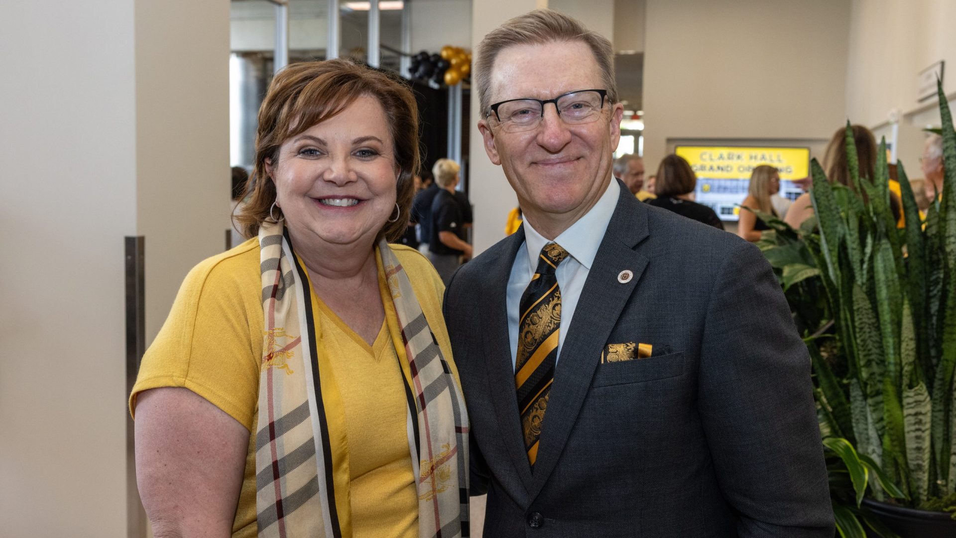a man and woman in black and gold attire pose for a photo