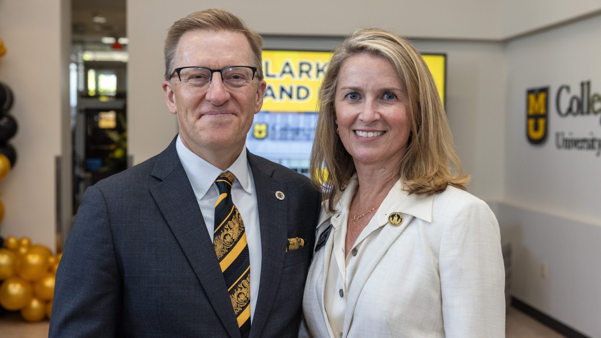 a man and woman in business attire pose for a photo