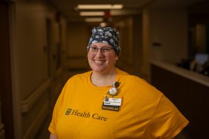 A woman in a yellow shirt stands in a hallway