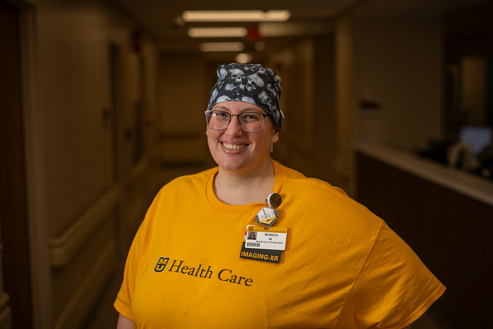 A woman in a yellow shirt stands in a hallway