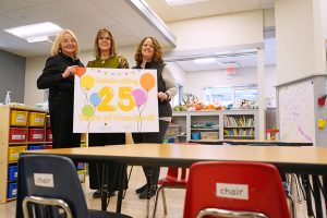 Three woman hold a sign