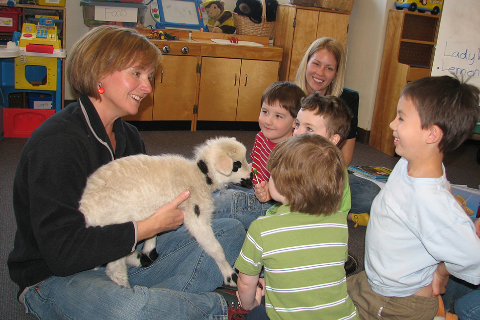 A woman and children pet a lamb
