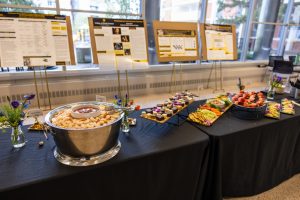 table of appetizers in front of easels holding student research posters