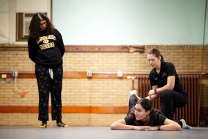 Two women demonstrate dance technique to another woman