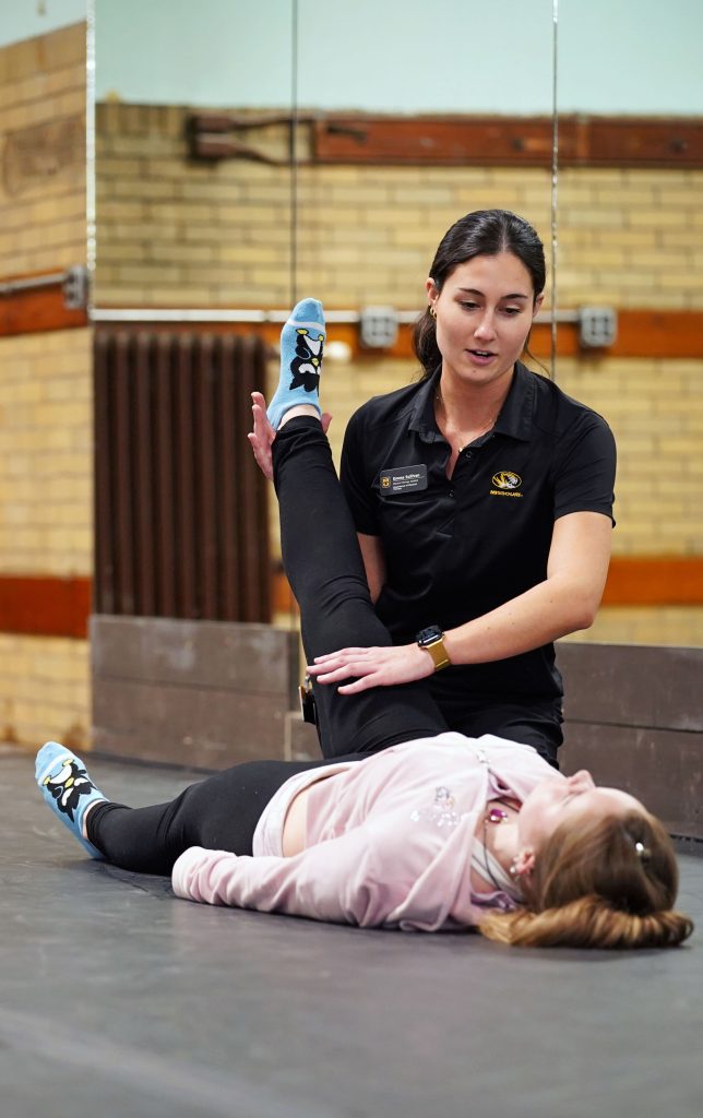 A woman helps another woman stretch