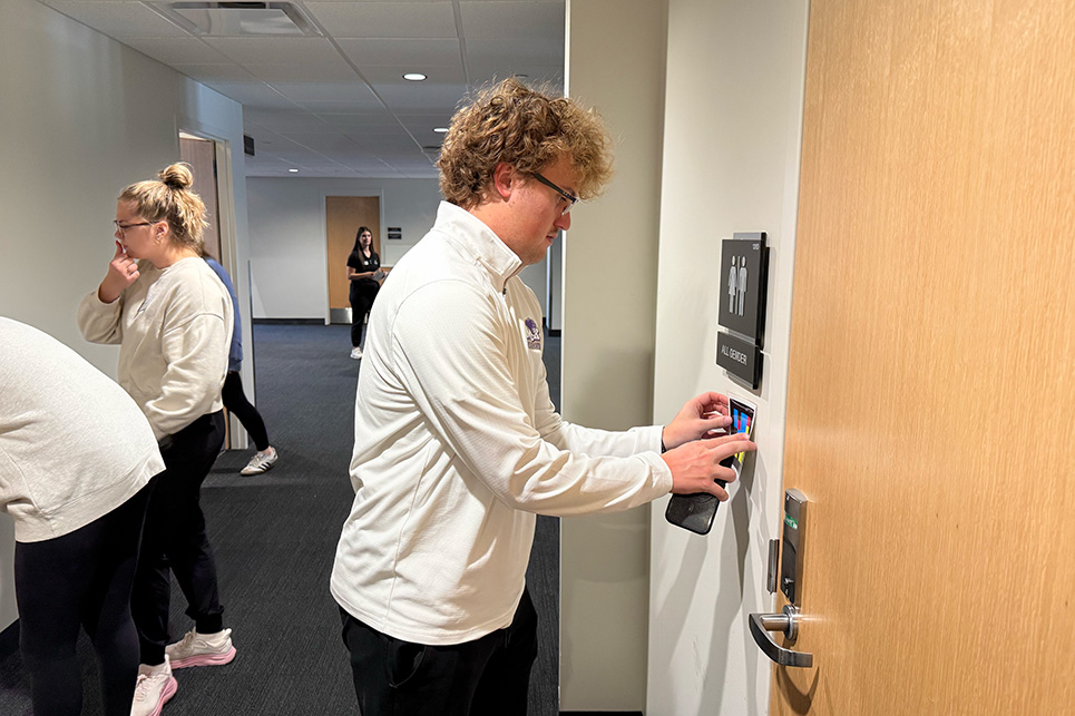 A man tapes a laminated piece of paper to a wall