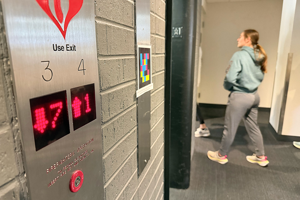 A QR code is taped to a wall near elevators