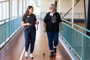 Two women walk along an indoor track